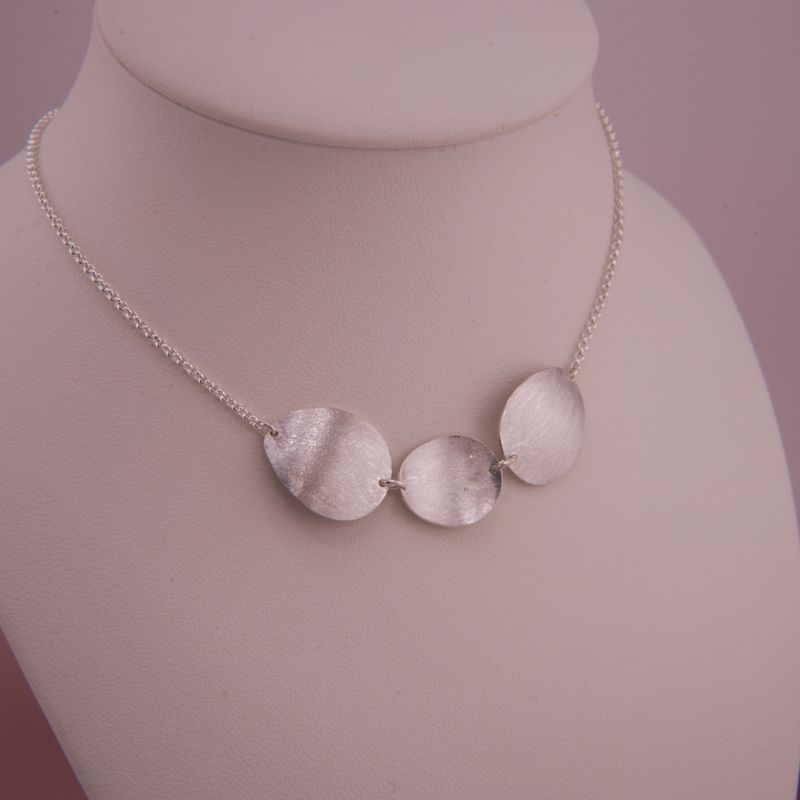Preview: Das gewendete Isola Silber-Collier auf der Präsentationsbüste mit der zweiten Trage-Option (mittiges Plättchen konvex).